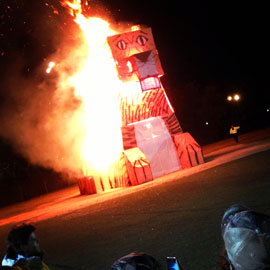 A large tiger made by engineering students ablaze while spectators watch.